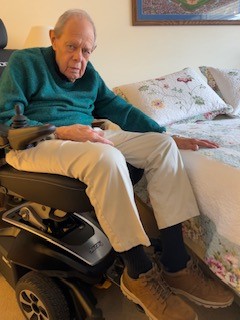 Author's father able to reach top of bed because of power seat elevation wheelchair