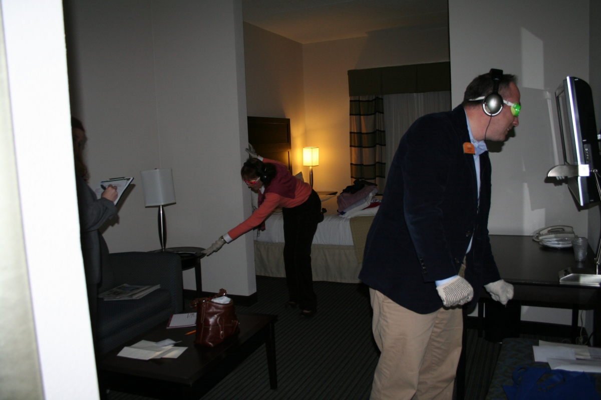 Virtual Dementia Tour participants navigate a simulated bedroom and dining area