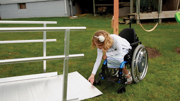 Natalie examines her new wheelchair ramp after installation by a group from EZ-ACCESS.
