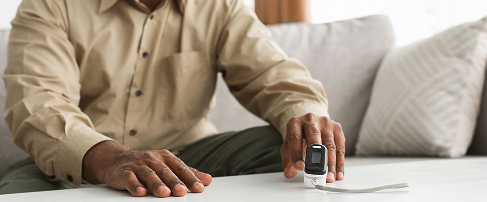 Black man checks oxygen levels using spirometer