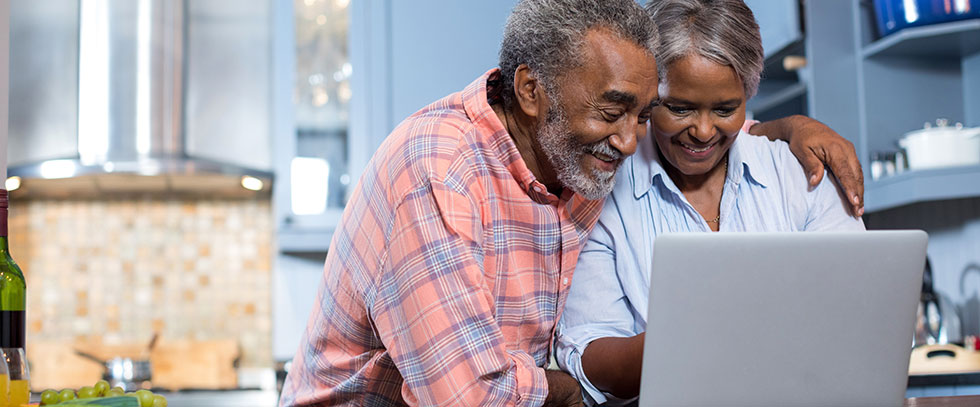 Older brown couple smiling at a computer