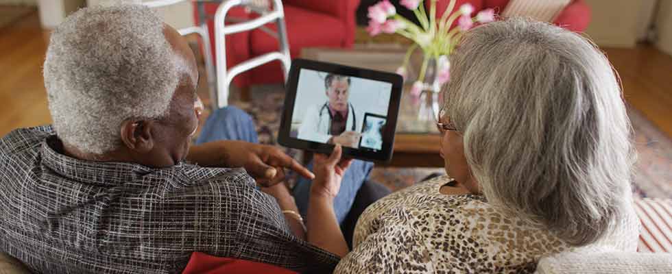elderly Black couple chats with doctor on iPad