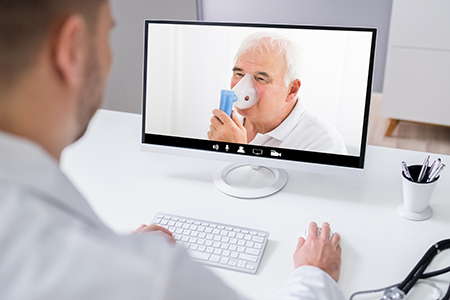 older white man uses nebulizer while on video call