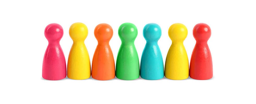 A set of multicolored blocks that look like people, ranging from red, orange, yellow, green, blue and pink set up in a line.