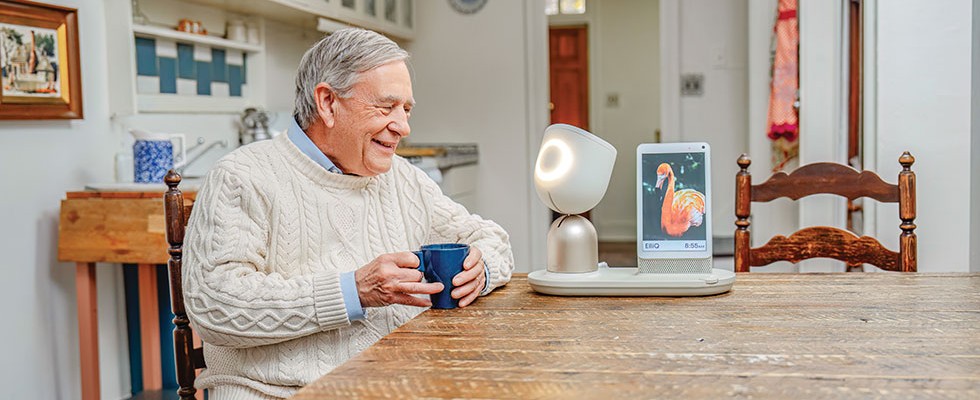 A senior man with an ElliQ, an outgoing digital assistant designed to engage with older people.