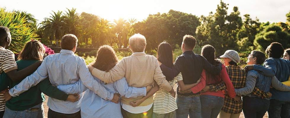 A group of people standing together staring off at a sunset