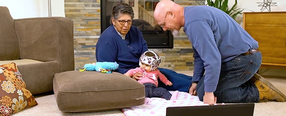 baby in a helmet working with man and woman .