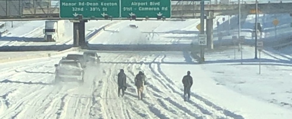 people waling on snowy interstate