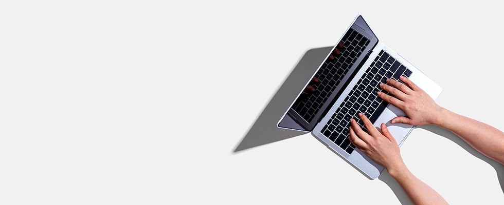 Hands typing on a laptop keyboard.