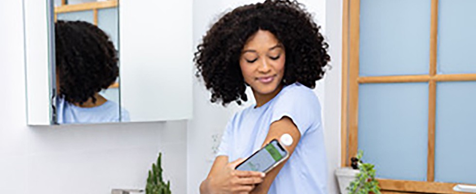 A woman uses her phone to see information from her continuous glucose monitors