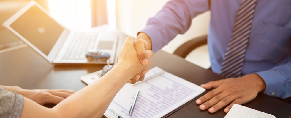 n image of two people shaking hands across a desk. 