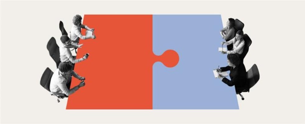 Members of a board sit at a table designed to look like a puzzle piece.