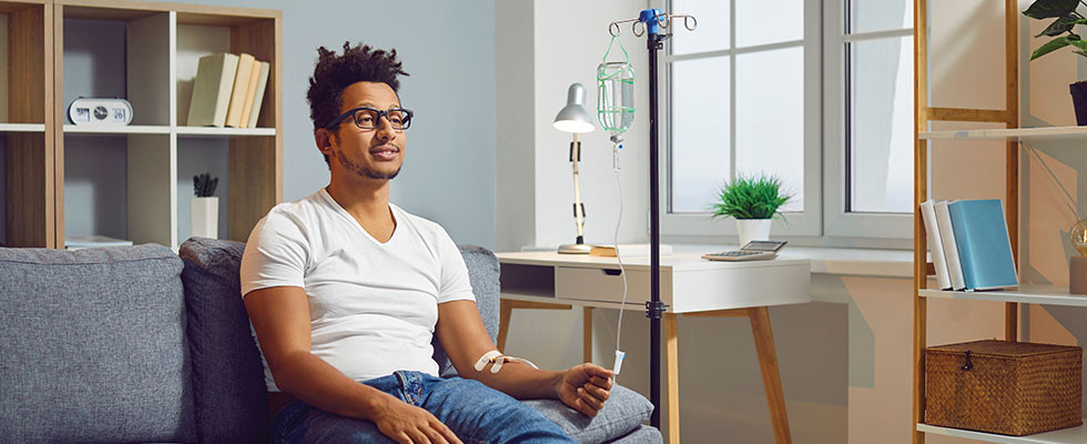 A man sitting on a couch receiving a home infusion therapy