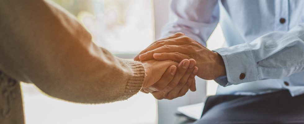 Two people holding hands in a hospice setting