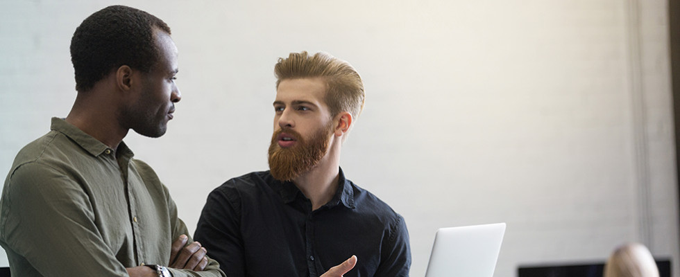 Two men talking while referencing a computer screen