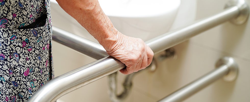 An image of an elderly person holding onto support bars