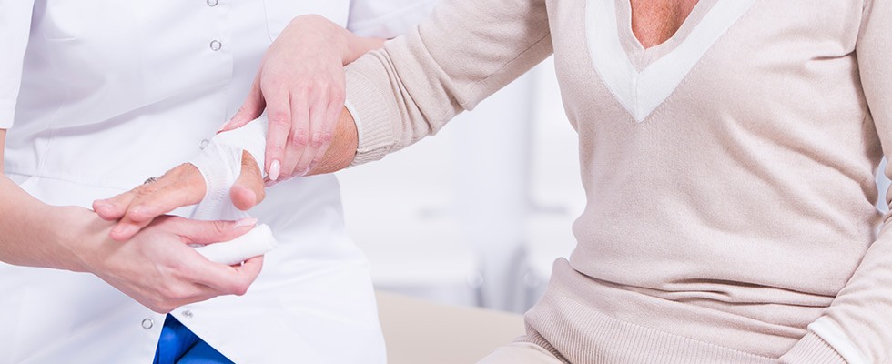 An image of a caregiver wrapping a woman's hand in gauze