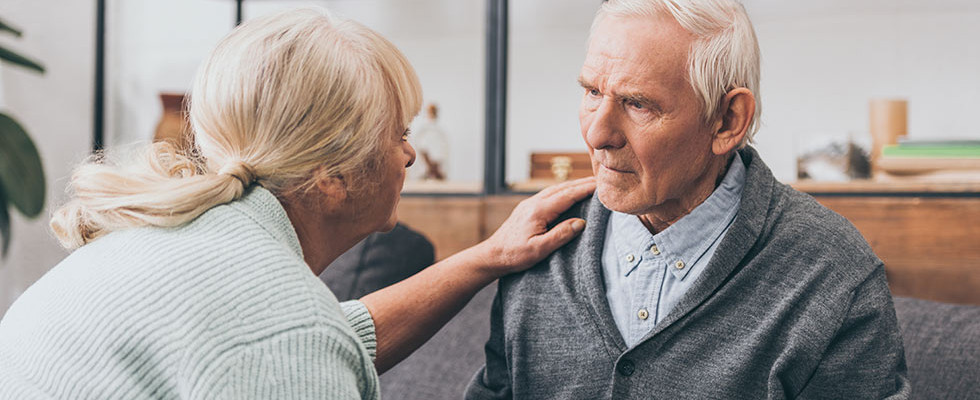 Two elderly people talking closely with each other.