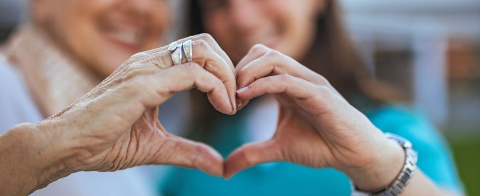 Two people hold their hands together to make the shape of a heart.