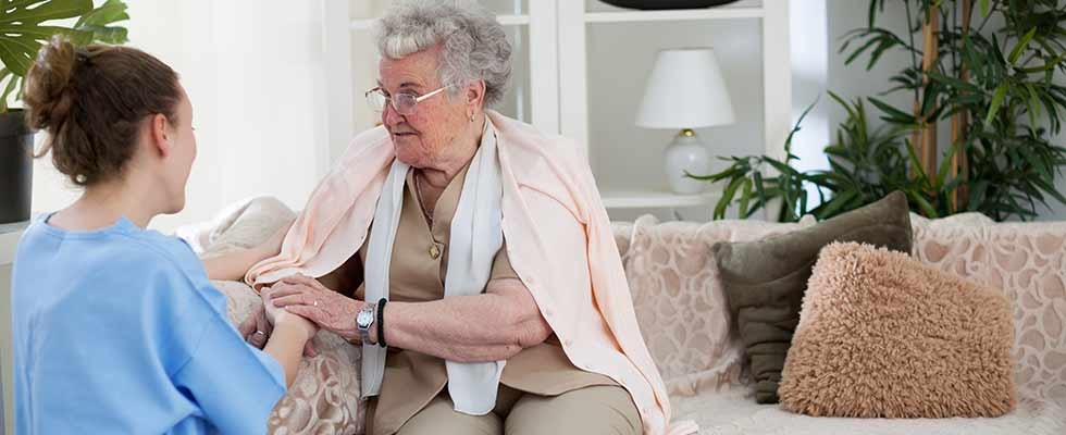 older white woman holding hands with white female nurse