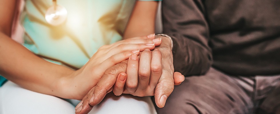 A caregiver and older adult holding hands
