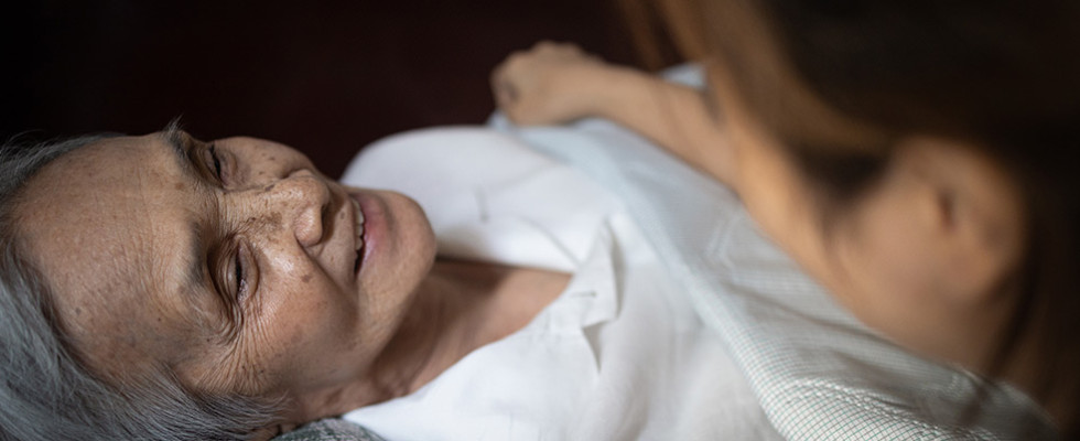 An elderly woman looking up at her caregiver