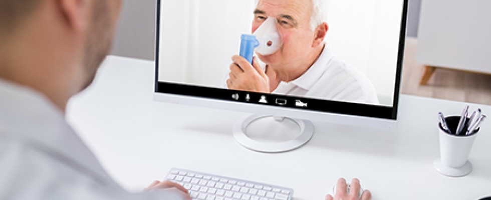 older white man uses nebulizer while on video call