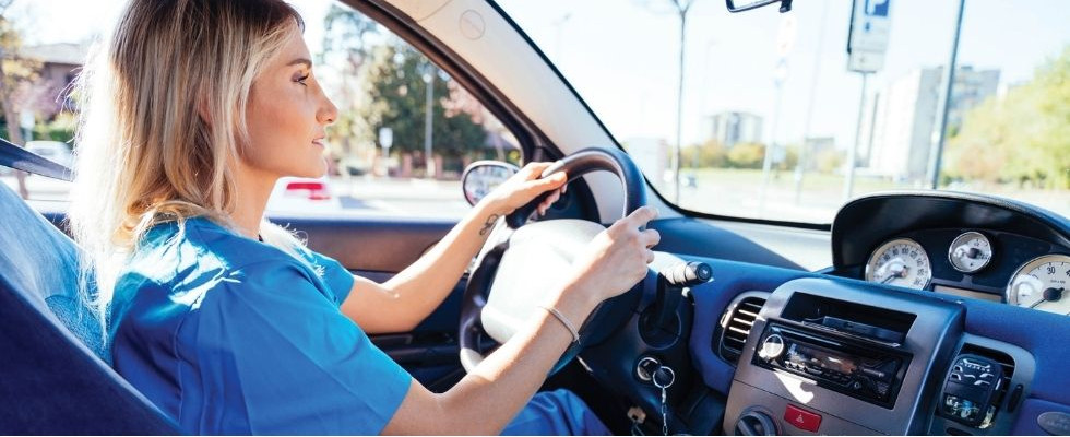 A woman in scrubs driving a car.