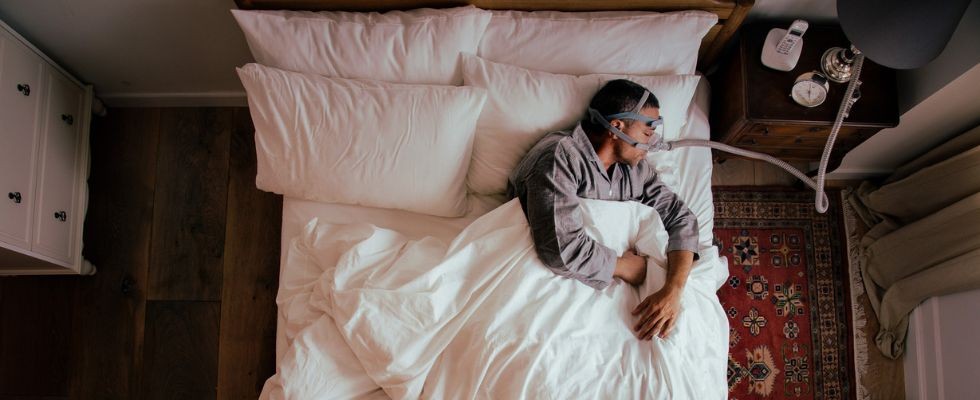 A man in a bed with a CPAP machine on sleeping