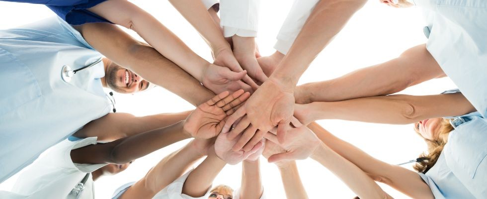 health care professionals putting their hands in to a pile for a celebration cheer