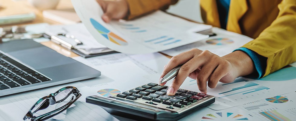 black female hand looks at pie chart and punches numbers into calculator