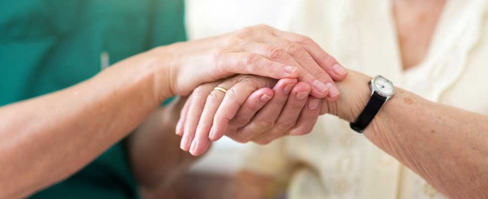 nurse holding older woman's hand