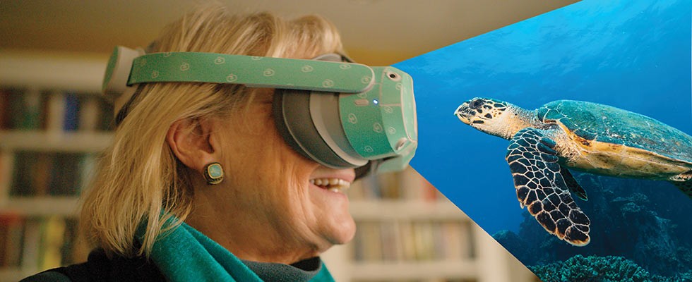 A woman wearing virtual reality smiling at a sea turtle