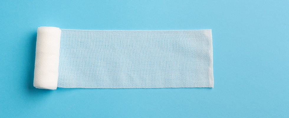 A roll of gauze laid out on a bright blue background
