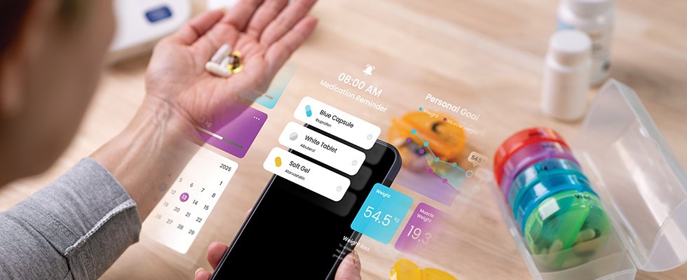 A person holding an iPhone with several screen widgets off to the side as well as a medicine organizer