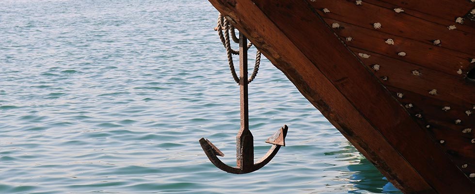 A ship anchor hanging above the water