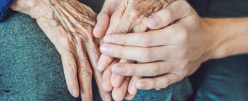 Two elderly hands being held by a younger hand.