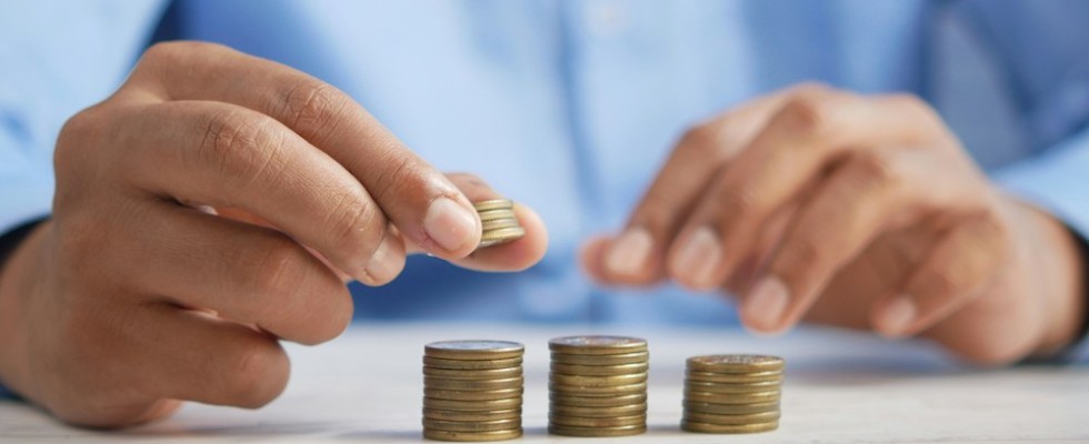 Two hands stacking coins into three columns