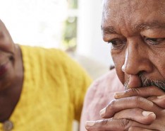 black senior woman comforts black senior man