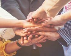 Multiple people in a huddle putting their hands in. 