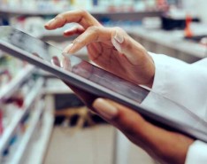 An image of a pharmacist on a tablet in front of stock, cataloging medication