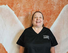 Doris LaPorte standing in front of large angel wings while smiling