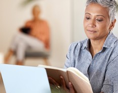 An image of a black woman with short hair reading a book