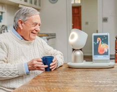 A senior man with an ElliQ, an outgoing digital assistant designed to engage with older people.