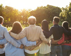 A group of people standing together staring off at a sunset
