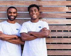 two young black men agains a brown horizontal fence