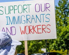 A person holding a sign that says ,"Support Our Immigrants and Workers"
