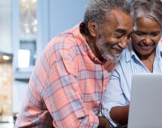 Older brown couple smiling at a computer
