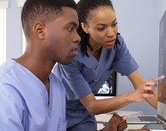 one black male nurse and one black female nurse looking at a computer screen