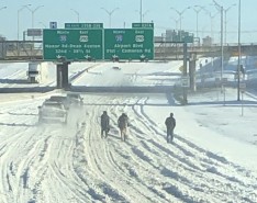 people waling on snowy interstate